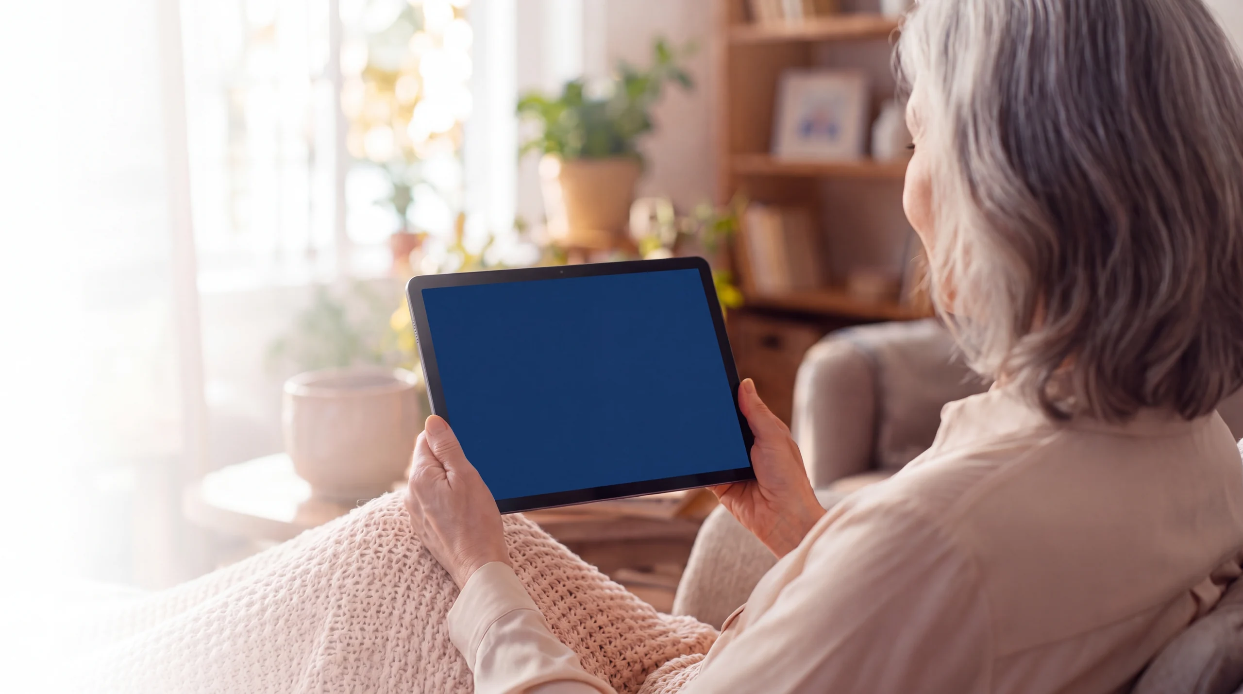 Una mujer mayor habla por vídeo en su tablet con la Asistente Emocional de NA.IA.